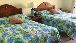 A hotel room with two beds, each with floral bedding, a nightstand with a lamp, and wall sconces. - BEACHFRONT STUDIO APARTMENT WITH GREAT VIEW OF THE OCEAN. (Cabarete)