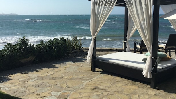 A beachside bed with a canopy, stone flooring, and a view of the ocean. - BEACHFRONT STUDIO APARTMENT WITH GREAT VIEW OF THE OCEAN. (Cabarete)
