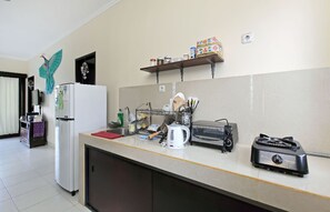 Une cuisine équipée d’un réfrigérateur, d’un grille-pain, d’une bouilloire et d’une étagère avec des bocaux.