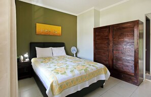 Une chambre à coucher comprenant un lit, une table de chevet, une commode, un miroir et une armoire.