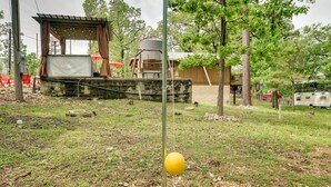 A rustic outdoor area with a stage, seating, and a yellow ball hanging from a pole.