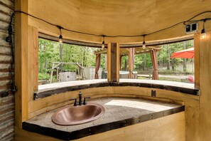 A rustic bathroom with a curved stone sink, wooden beams, and a view of the outdoors. - 2 Mi to Choctaw Landing: 'Western Daze' Cabin! (Broken Bow)