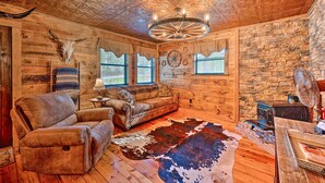 A rustic interior with wooden walls, a leather sofa, a cowhide rug, and a ceiling with a decorative fan.