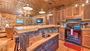A rustic kitchen with wooden cabinets, a large island with a sink, and a built-in oven.