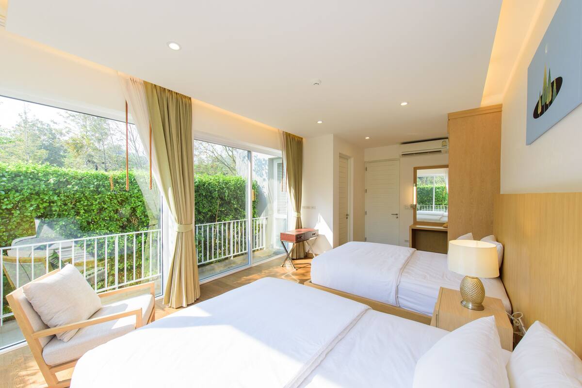Habitación de hotel con dos camas, un balcón y vistas a zonas verdes.