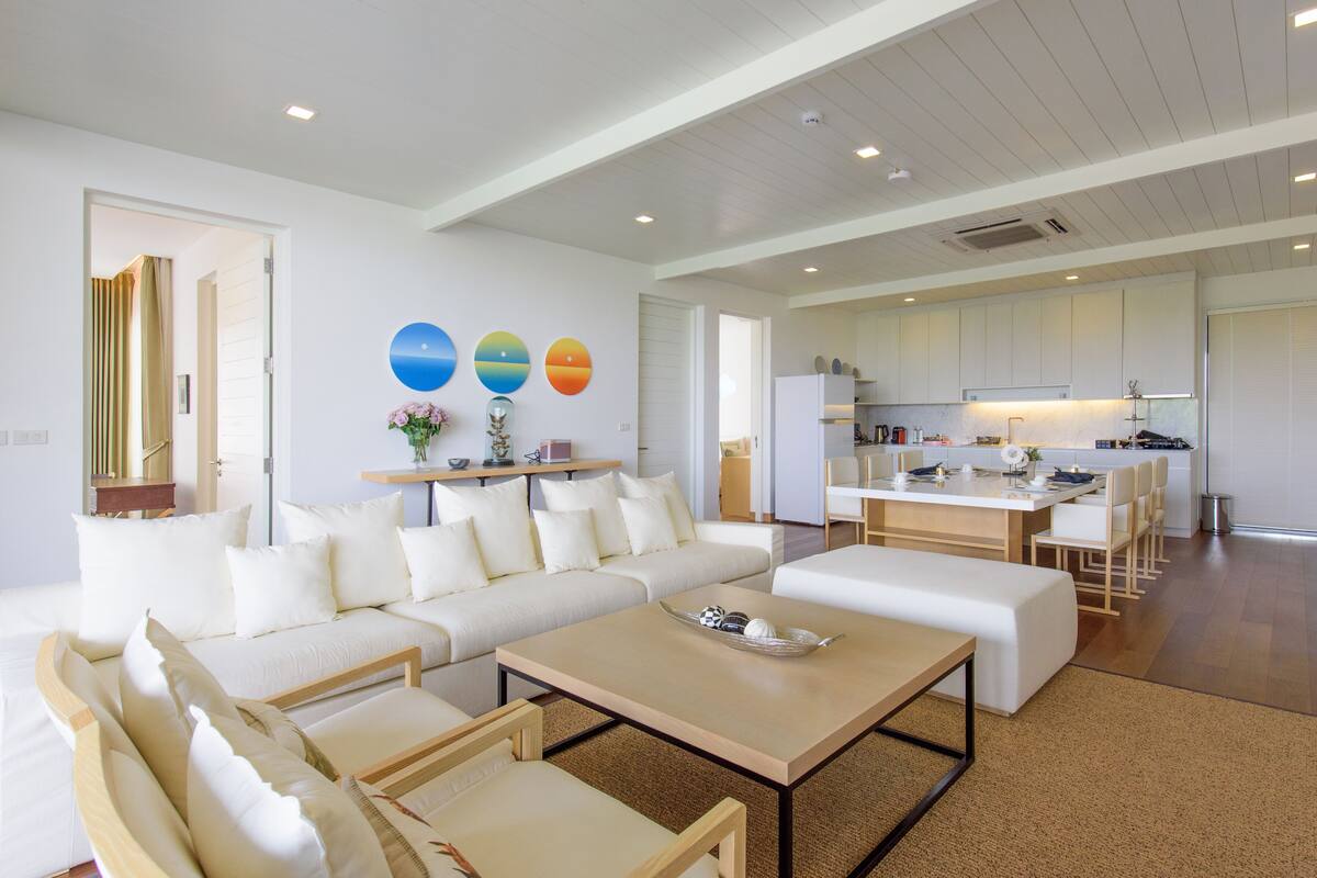 Una sala de estar moderna con un sofá, una mesa de centro y sillas. Cuenta con una zona de cocina con una mesa de comedor y sillas.