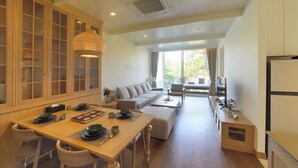 Amplia sala de estar con sofá, mesa de centro y mesa de comedor preparada para cuatro personas.