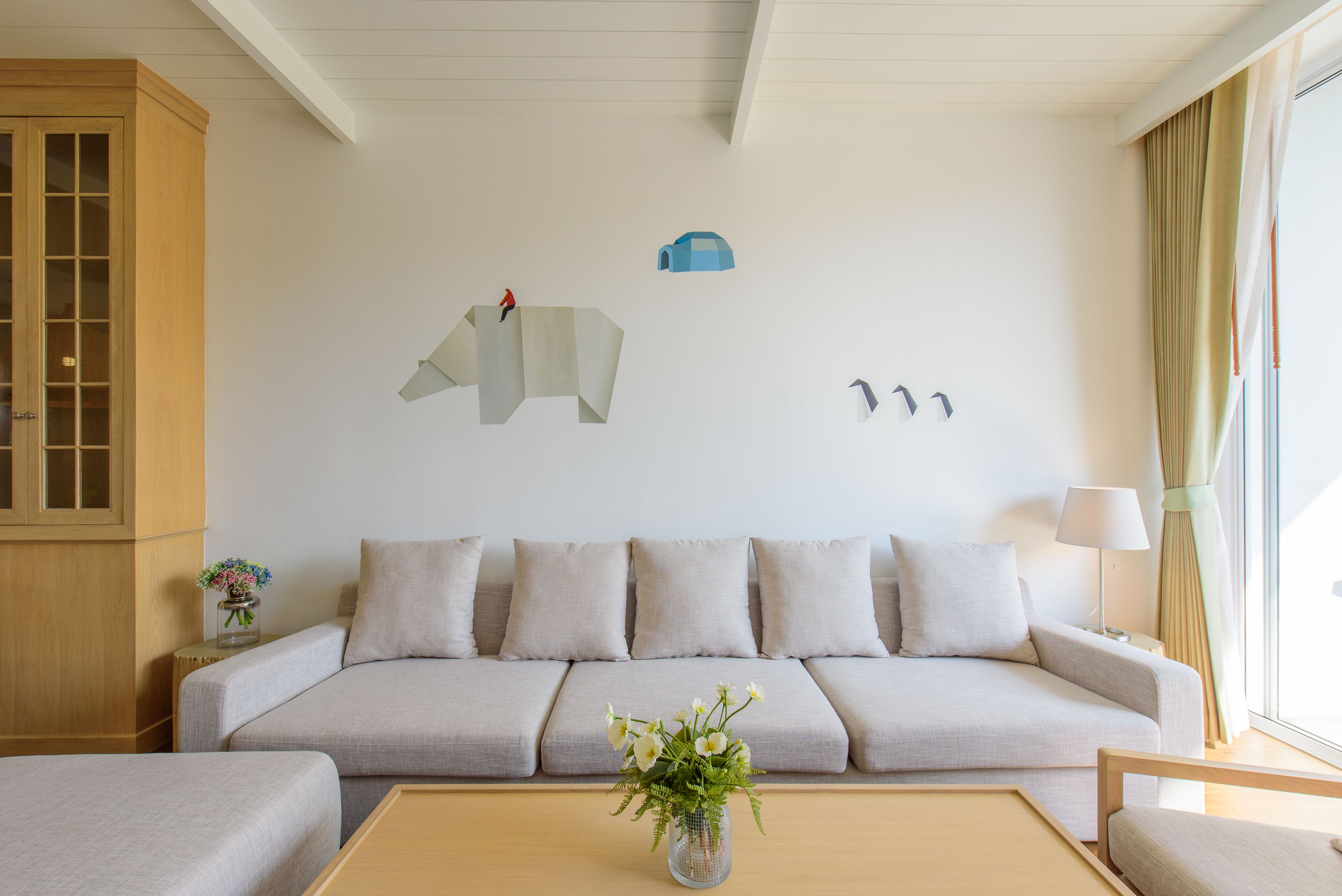 Una sala de estar moderna con un sofá, una mesa de centro con un jarrón de flores y una pared decorada con arte abstracto.