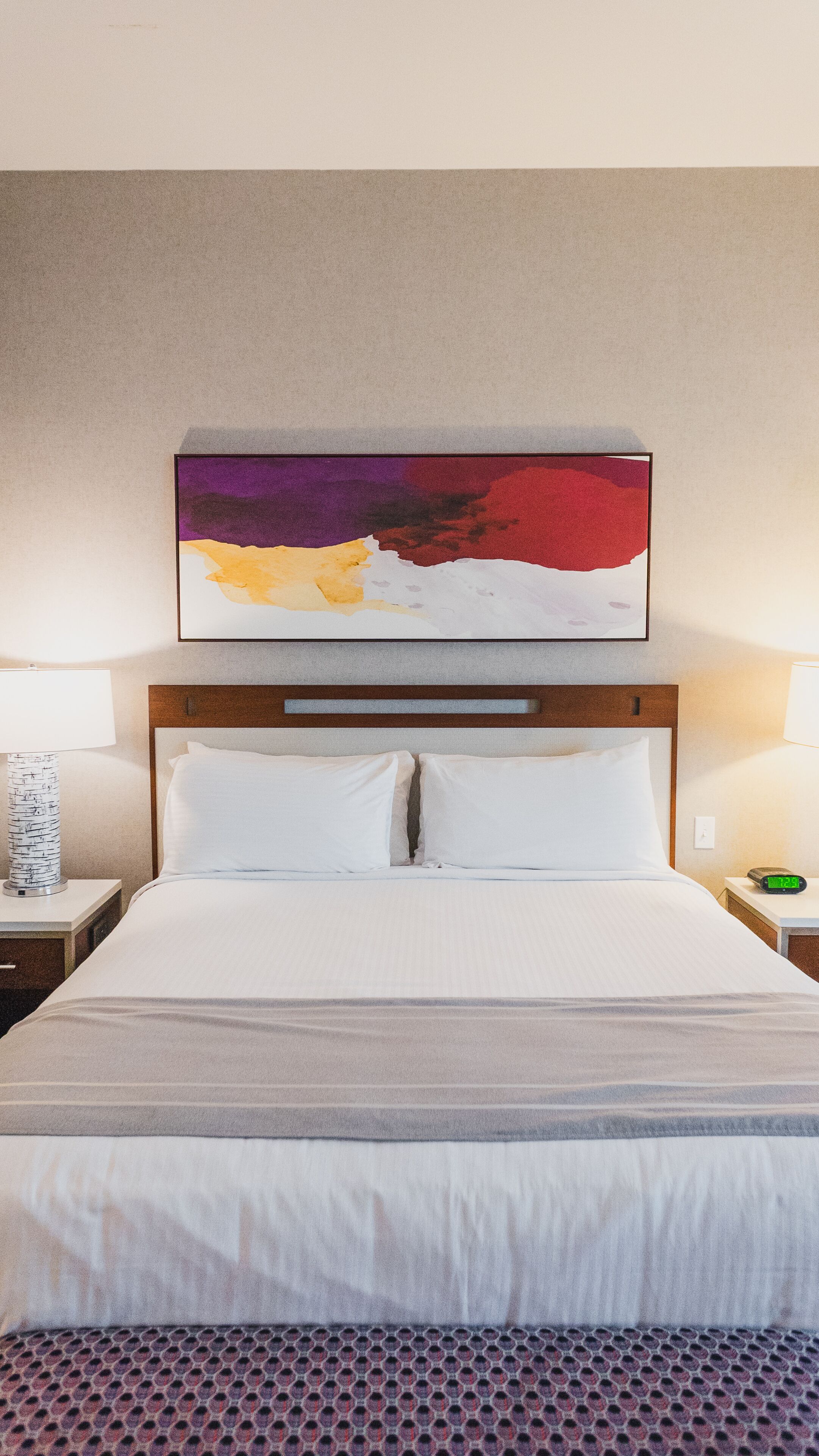 Una camera d'albergo con un letto grande, due comodini e un quadro appeso al muro.