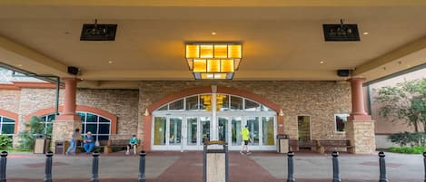 A building entrance with a stone facade, a glass door, and a central light fixture.