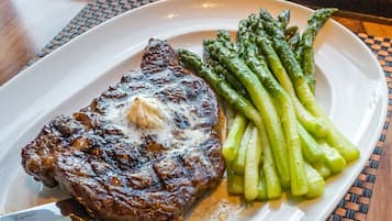 A plate with steak and asparagus on a woven placemat.