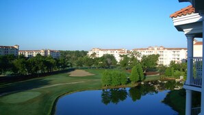 Ein Golfplatz mit Teich, umgeben von mehrstöckigen Gebäuden mit einheitlichem Baustil.