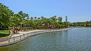 Eine Uferpromenade mit Palmen, einer Brücke und einem Turm im Hintergrund.