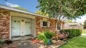 A residential house with a brick facade, a front porch, and a well-maintained lawn.