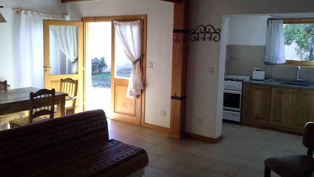 Una cocina acogedora con armarios de madera, una estufa y un ventanal con cortinas.
