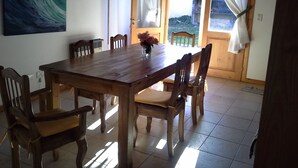 Un comedor con una mesa y sillas de madera, un florero con flores y un cuadro en la pared.