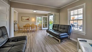 Ein Wohnzimmer mit schwarzem Ledersofa, einem Esstisch mit Stühlen und einem Balkon mit Blick.