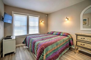 Ein Schlafzimmer mit einem Bett, einem Schminktisch, einem an der Wand montierten Fernseher und zwei Wandleuchten.