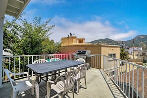 Ein Balkon mit Tisch, Stühlen und Grill, mit Blick auf einen Berg.