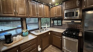 Una cocina con armarios de madera, microondas, estufa y lavaplatos.