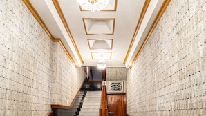 Interior de un hotel con una escalera de mármol, un candelabro y un letrero que dice 'Don Saul Hotel'.