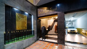 La entrada del Hotel Don Saul, con un diseño moderno, una escalera visible y un área de estacionamiento.