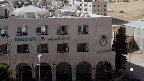 A building with the Al Majjar Hotel logo, featuring multiple balconies and arched windows.