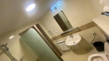 Ein Badezimmer mit Dusche, Waschbecken, Toilette und Spiegel.