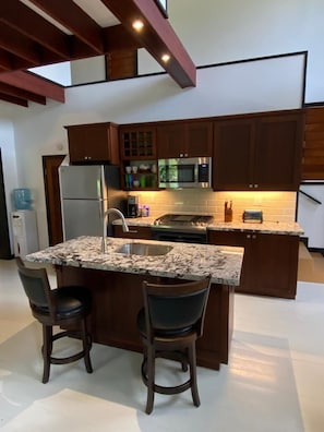 Enjoy cooking in this well-equipped kitchen with a central island, sink, and bar stools.