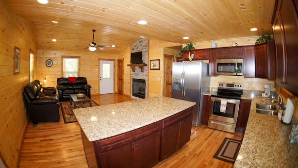 A wooden cabin interior with a kitchen, living area, and fireplace. - Cabin in the Woods-Gas Fireplace - Charcoal Grill - Pet Friendly (Whittier)