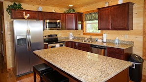 A kitchen with wooden cabinets, granite countertops, stainless steel appliances, and a window with a view. - Cabin in the Woods-Gas Fireplace - Charcoal Grill - Pet Friendly (Whittier)
