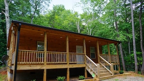 A wooden cabin with a covered porch and a staircase leading to the entrance. - Cabin in the Woods-Gas Fireplace - Charcoal Grill - Pet Friendly (Whittier)