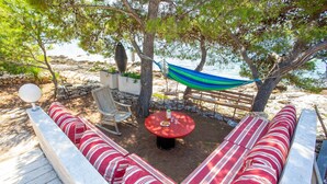 A beachside seating area with a hammock, a round table, and striped cushions. - Family house Futura  (Milna)