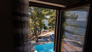 A view of a swimming pool with blue water, surrounded by trees and outdoor seating. - Family house Futura  (Milna)