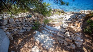 A stone pathway leading to a stone wall with a view of the sea. - Family house Futura  (Milna)