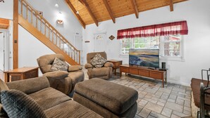 A spacious living room with a high wooden ceiling, a staircase, and a large window with a view. - Southern Comfort - AC, Hot Tub,Centrally Located, Fenced Yard, BBQ (Big Bear Lake)