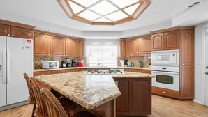 A modern kitchen with wooden cabinets, granite countertops, a central island, and built-in appliances. - Southern Comfort - AC, Hot Tub,Centrally Located, Fenced Yard, BBQ (Big Bear Lake)