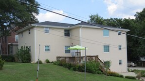 A two-story building with a flat roof, a covered deck, and a small front yard.