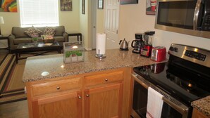 A compact kitchen with a granite countertop, a coffee maker, a toaster, and a microwave.
