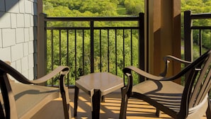 Ein Balkon mit Tisch und zwei Stühlen, mit Blick auf eine grüne Landschaft.