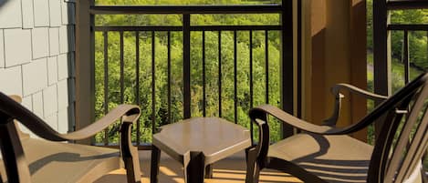 Un balcon avec une table et deux chaises, donnant sur un paysage verdoyant.