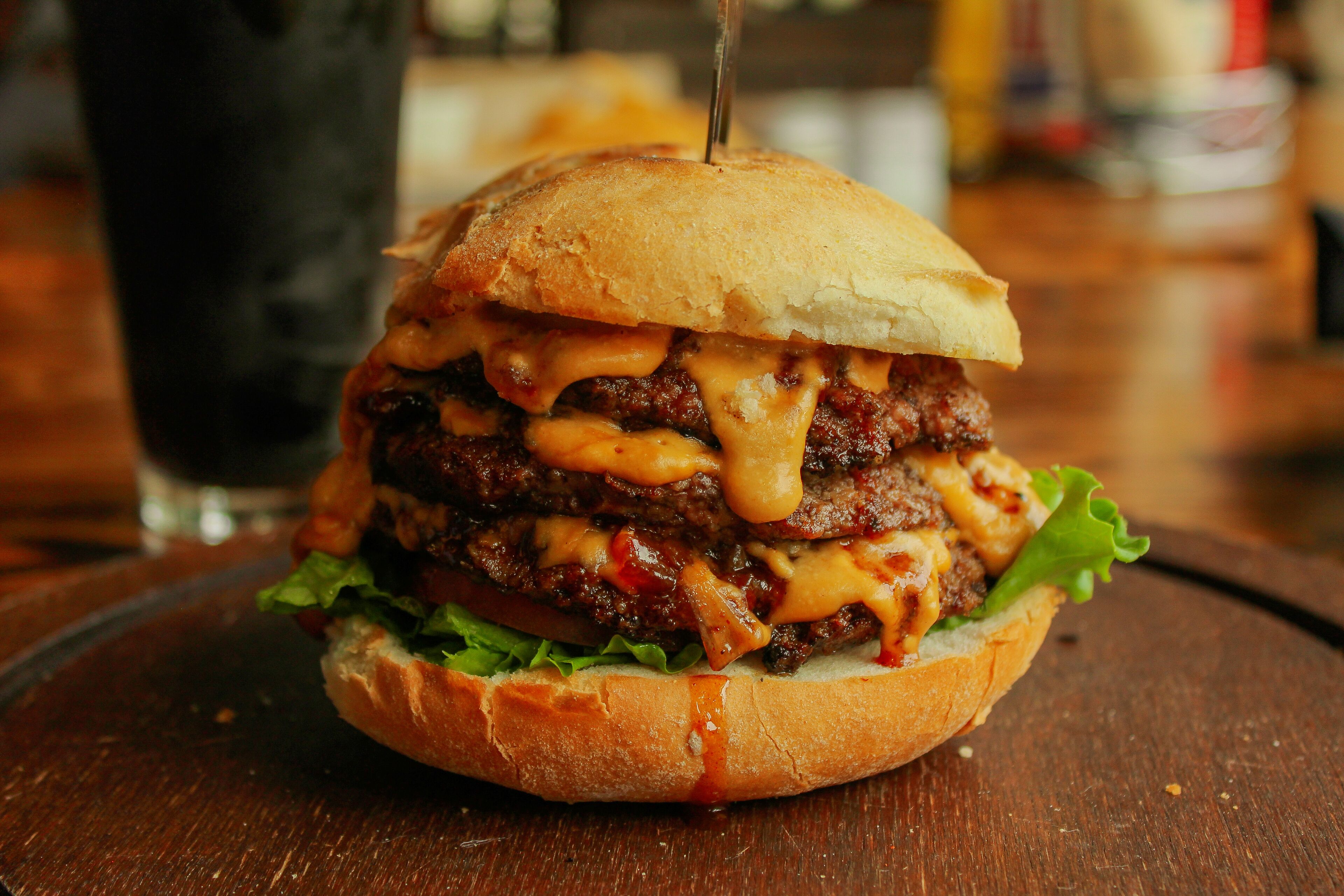 A burger with a toothpick in the center, placed on a wooden surface.