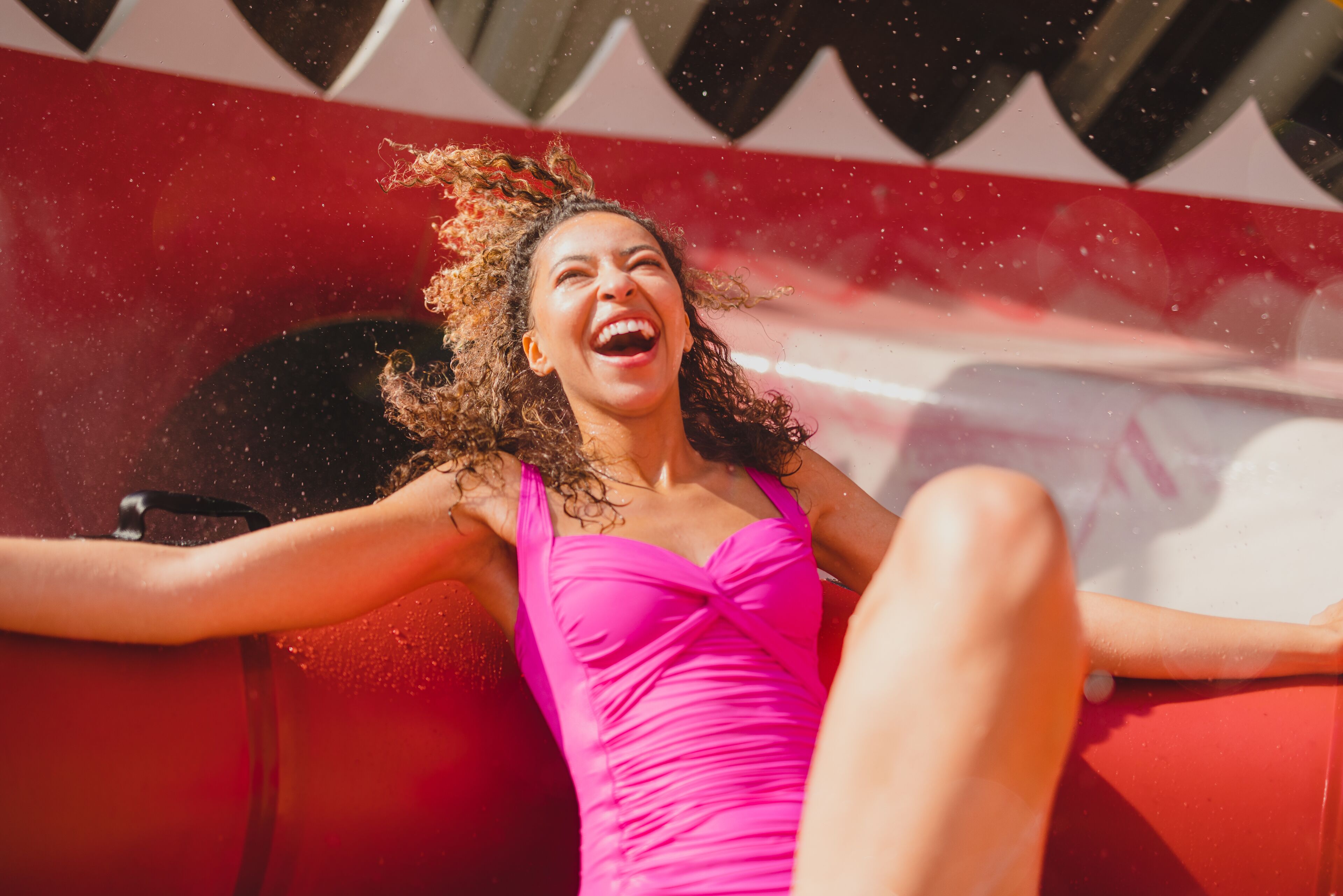 A person in a pink dress sitting on a red chair with arms outstretched.