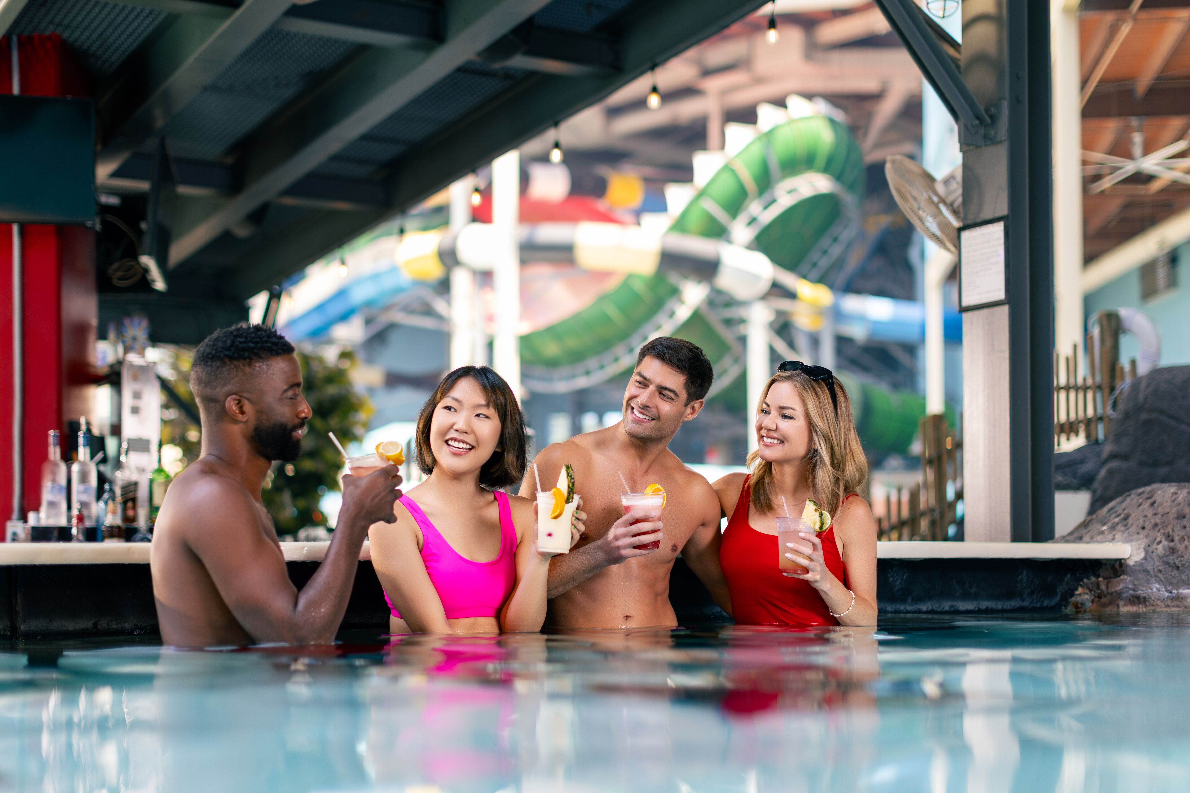 A group of people in a pool area with a water slide in the background.