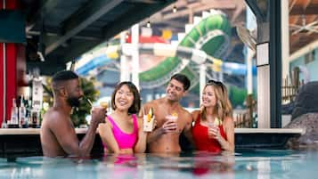 Un grupo de personas en un área de piscina con un tobogán de agua al fondo.