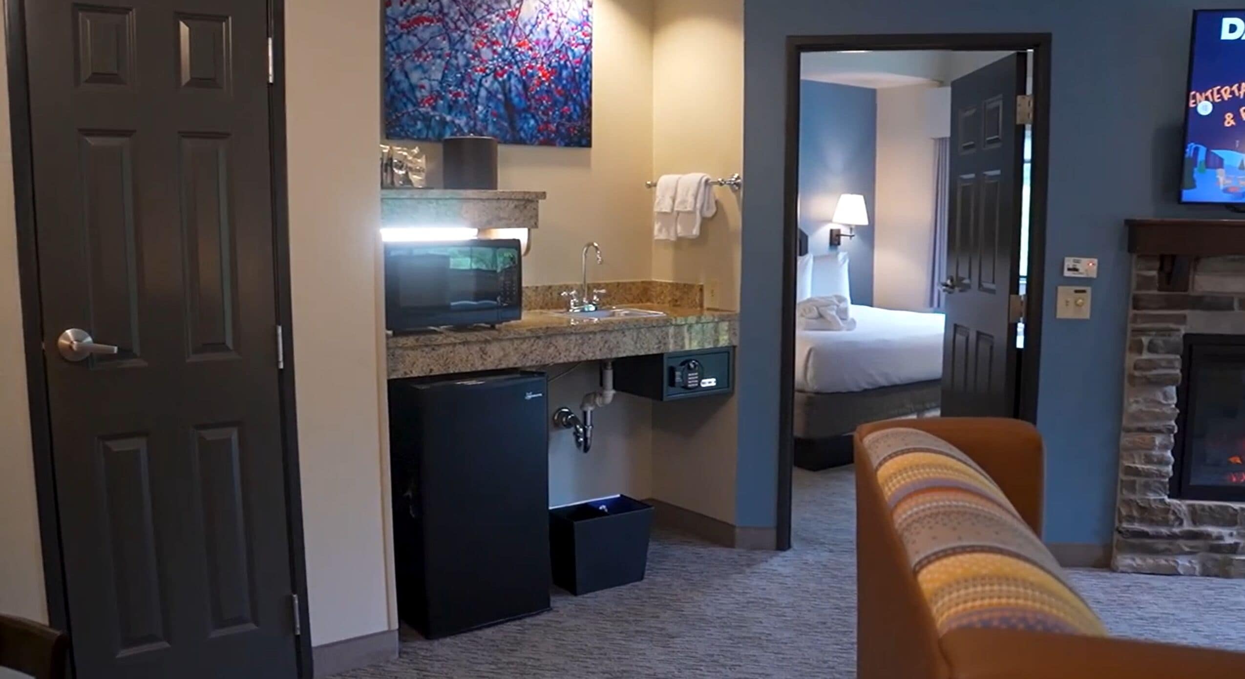 Een hotelkamer met kitchenette, een bed, een televisie en een open haard.