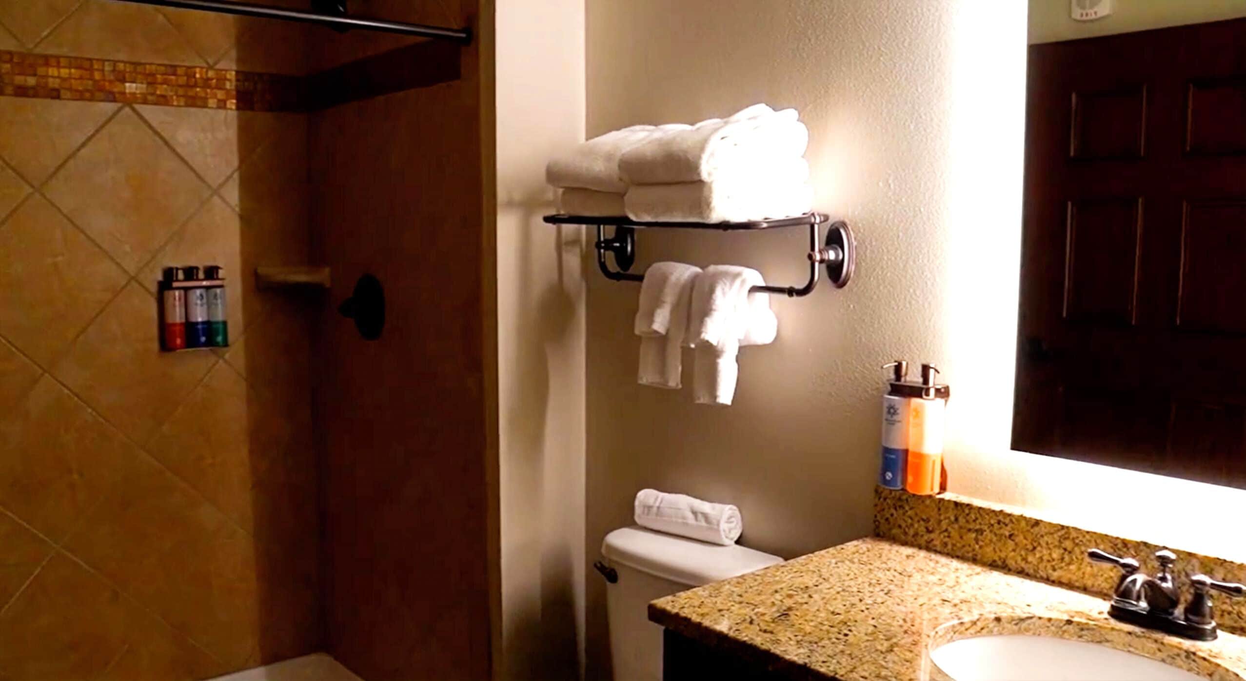 A bathroom with a shower, a toilet, a sink, and a towel rack with towels.