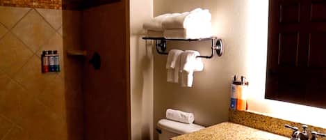 Un baño con ducha, inodoro, lavamanos y un toallero con toallas.
