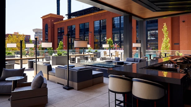 A modern outdoor lounge area with seating, a bar, and a view of a cityscape.