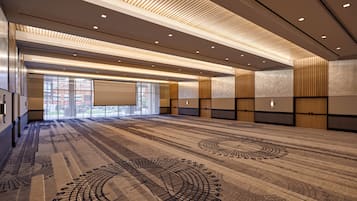 A spacious conference room with a patterned carpet, recessed lighting, and a large projection screen.